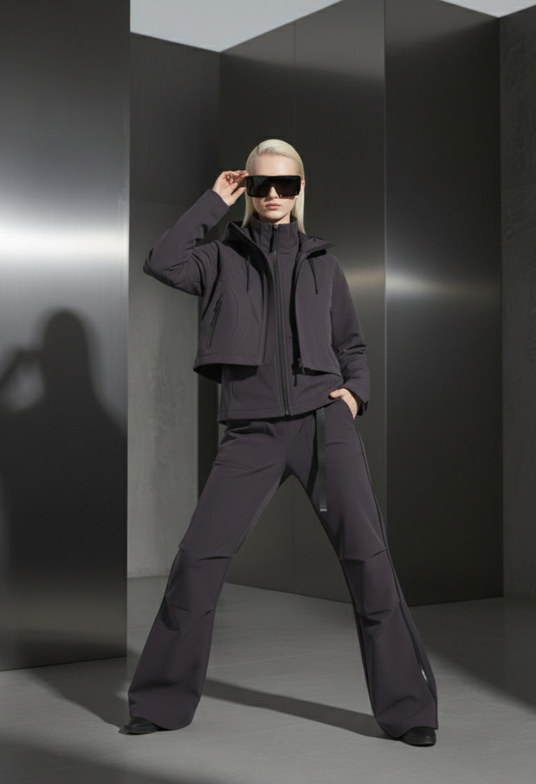Person wearing a dark outfit with sunglasses in a minimalistic setting