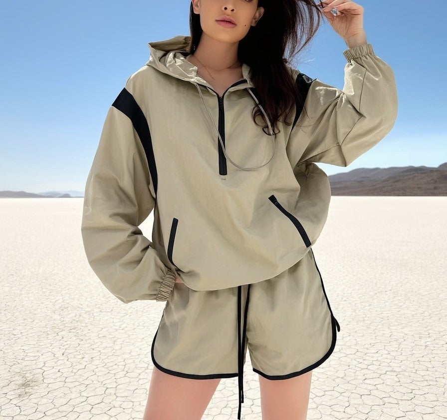 A woman wearing a beige matching sports wear tracksuit with black accents in a desert setting