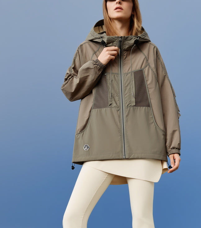 A woman wearing a green and brown outdoors fitness jacket against a blue background